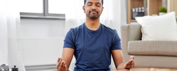 Homme pratiquant la méditation dans son salon